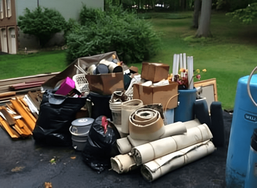 Pile of assorted household items outside house.