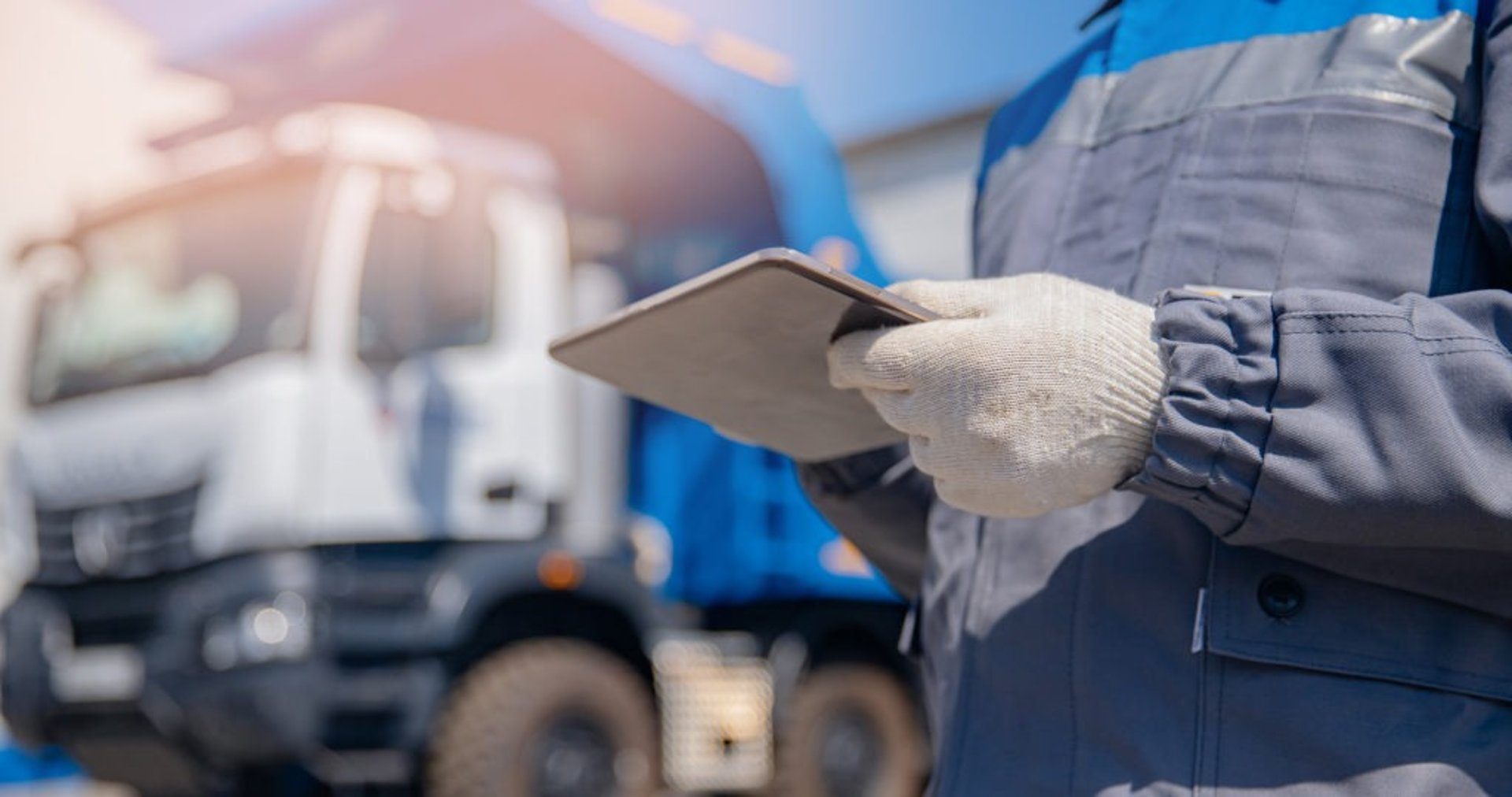 Worker holding tablet near truck.